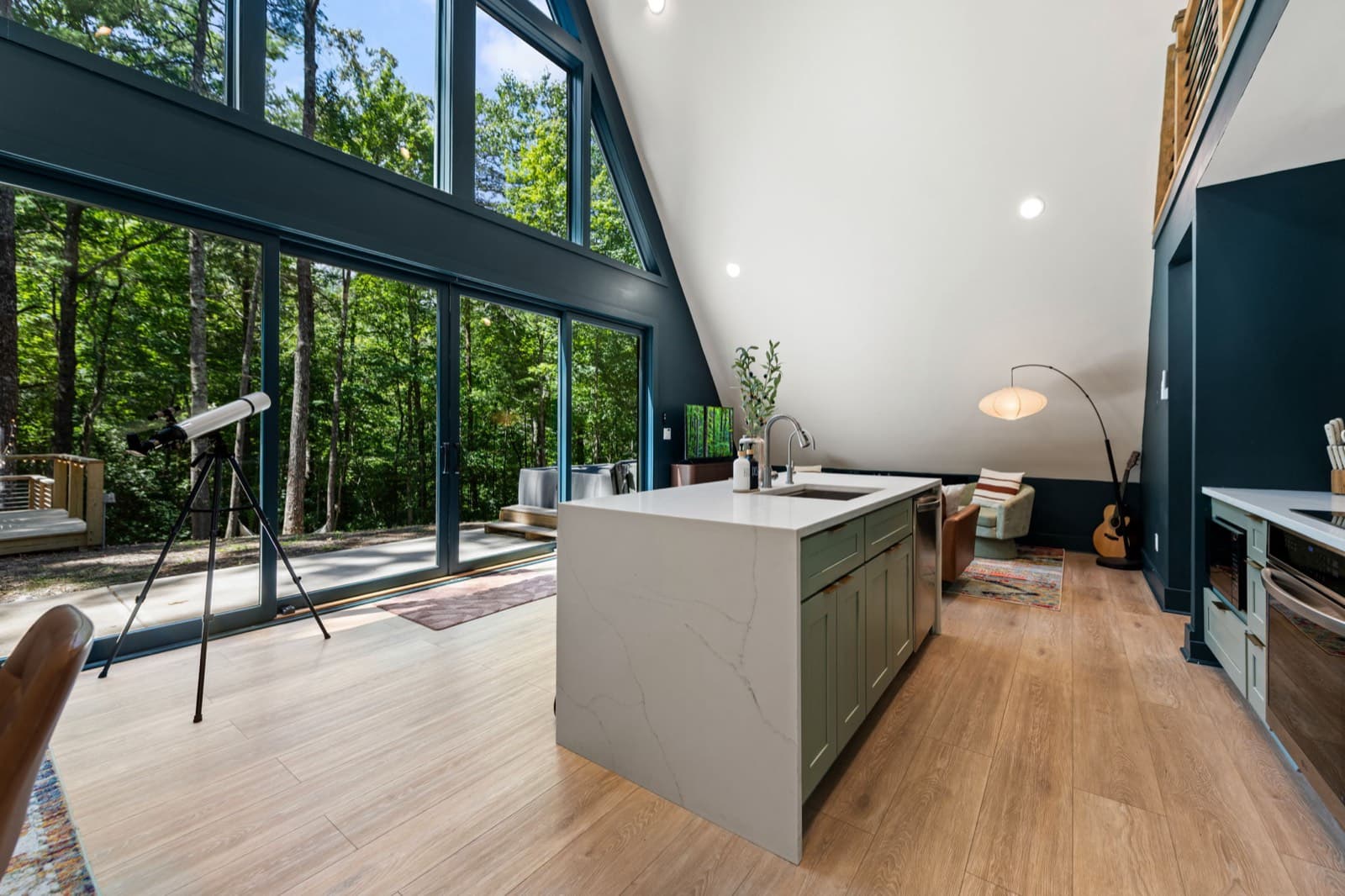 Open kitchen and great room with floor-to-ceiling windows into the forest